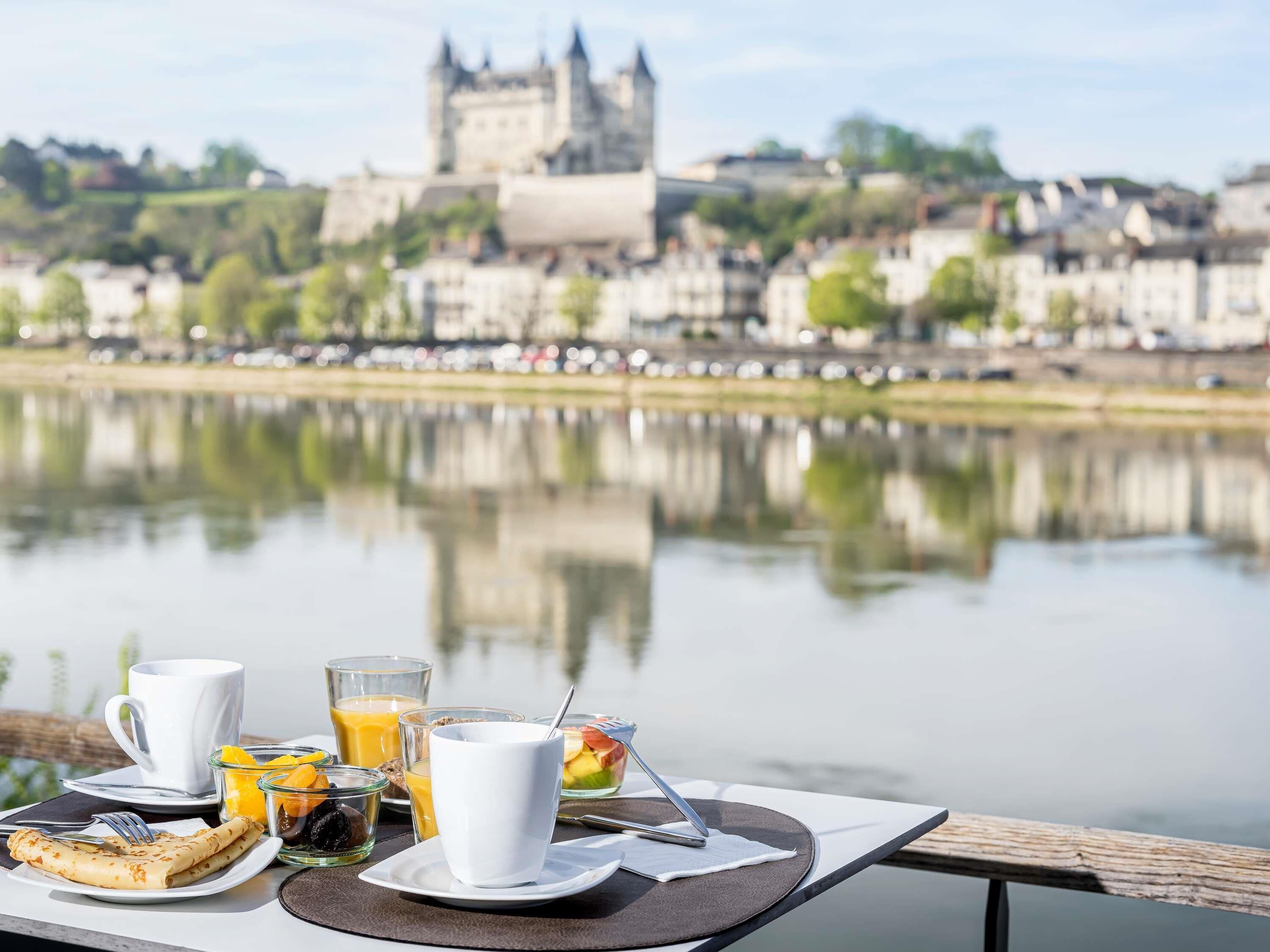 A breakfast table with a view of a castle across a river.