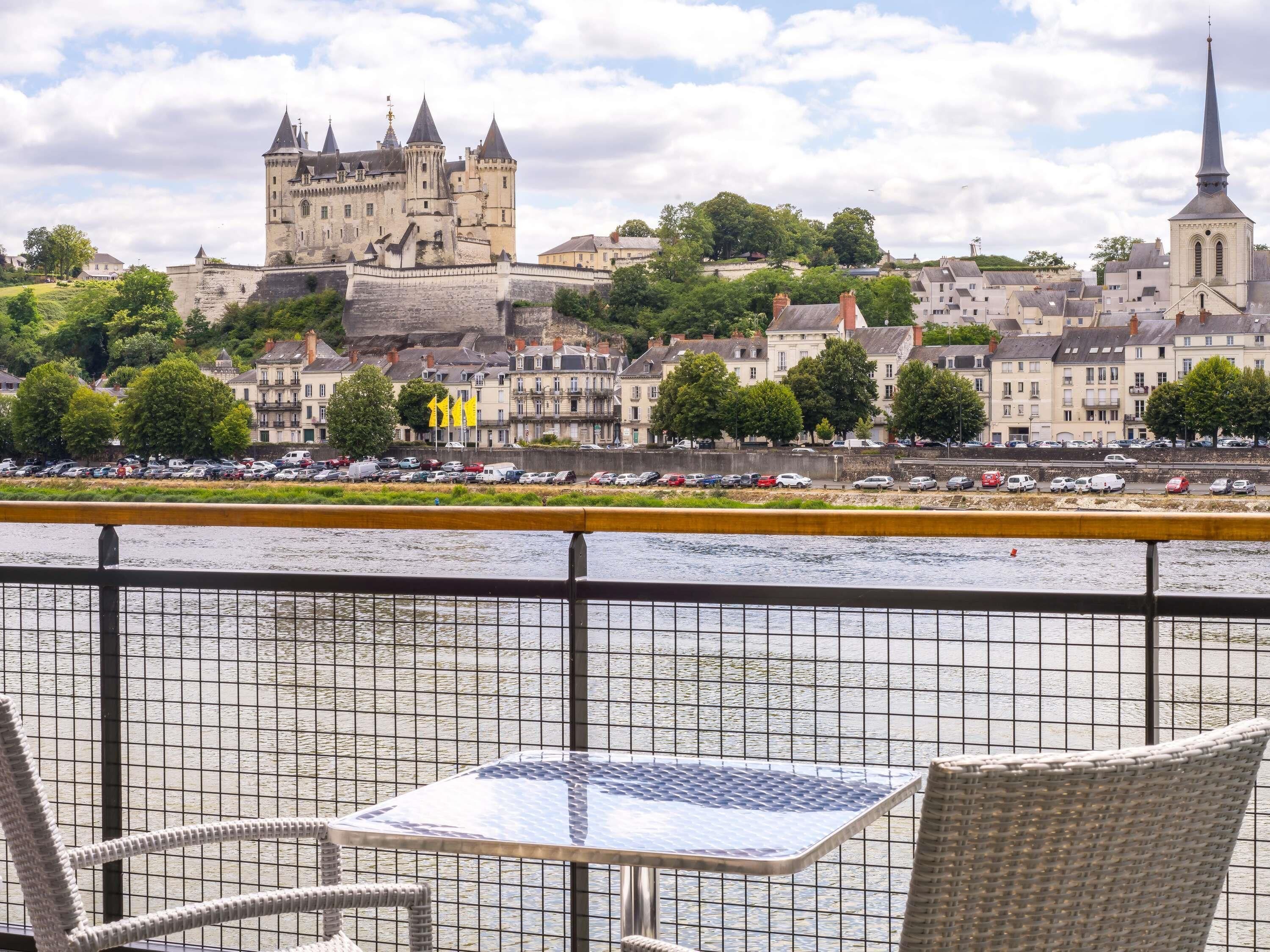 Aussicht auf einen Fluss mit Burg, Kirche und einer Reihe von Gebäuden.