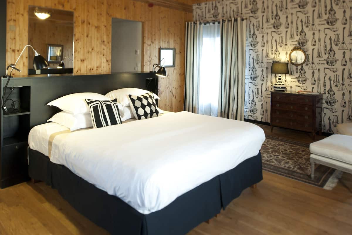 A neatly arranged bedroom with a large bed, bedside tables, a dresser, and a mirror.