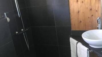Een badkamer met douche, toilet en wastafel.