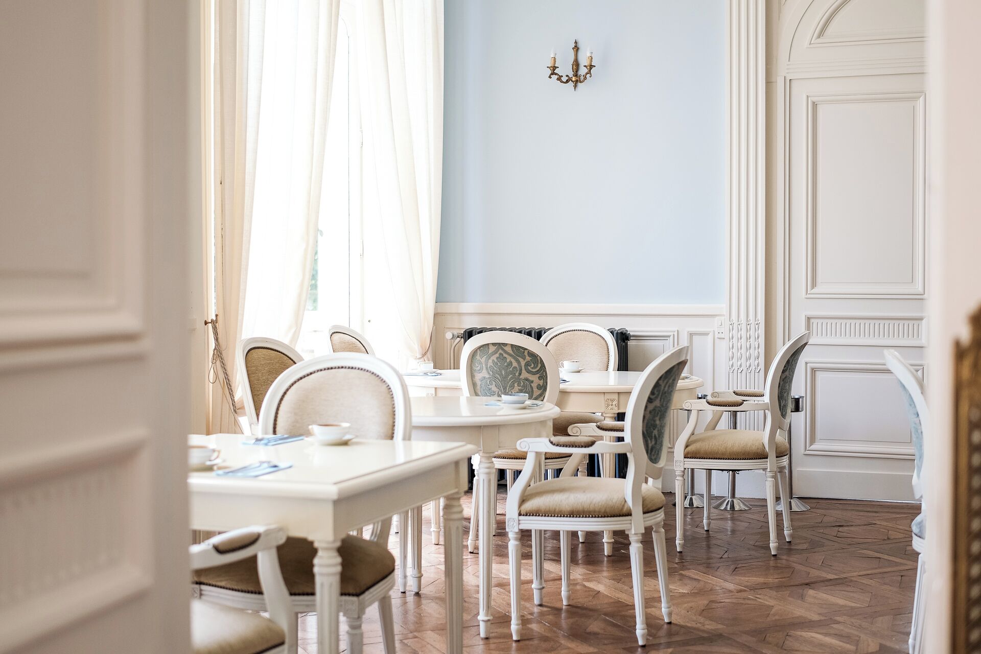 Un espace repas avec des meubles blancs et un parquet à motifs en chevrons.
