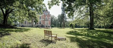Un parc avec un banc et un grand bâtiment en arrière-plan.