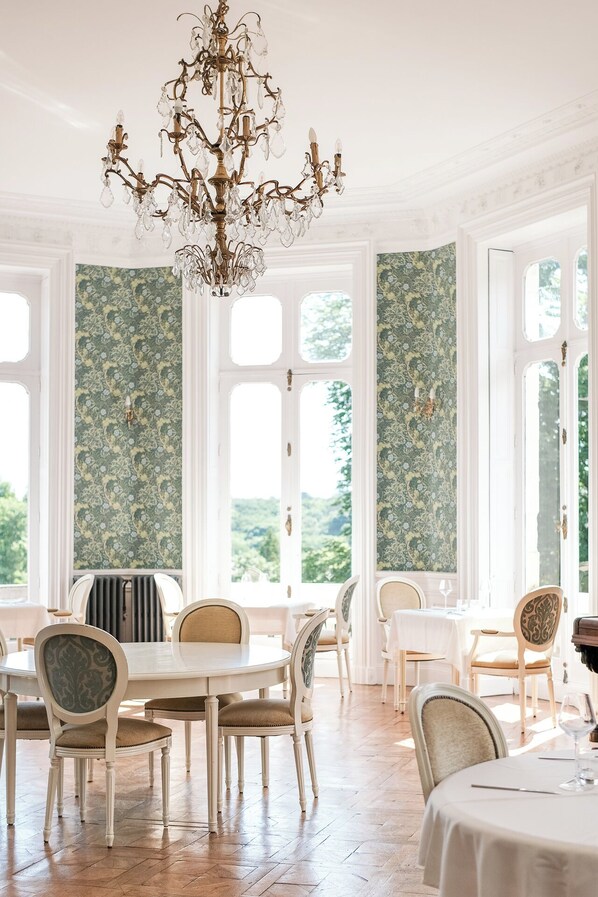 Comedor con candelabro, sillas blancas y mesa puesta para comer.