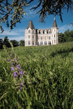 A large, historic building with two prominent towers, surrounded by lush greenery and a clear sky. - Château de l'Aubrière (La Membrolle-sur-Choisille)