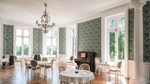 Una habitación amplia con techos altos, ventanas grandes y una imponente lámpara de candelabro.