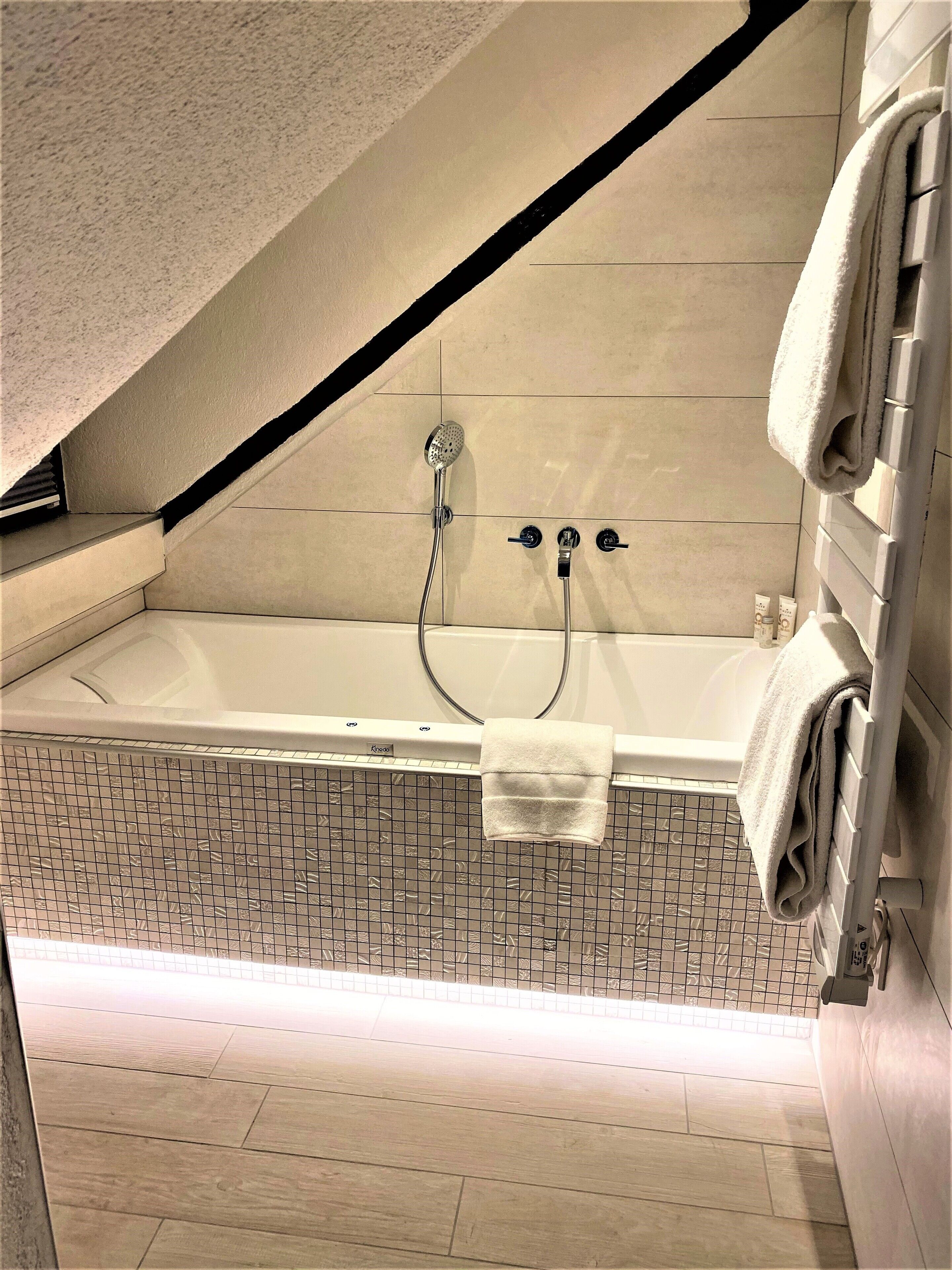 Un baño moderno con una bañera independiente, un cabezal de ducha y un perchero para toallas.