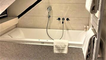 Un baño moderno con una bañera independiente, un cabezal de ducha y un perchero para toallas.