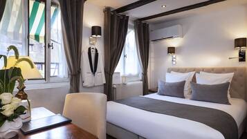 Una habitación de hotel con cama, una silla, una mesa y una ventana con cortinas.