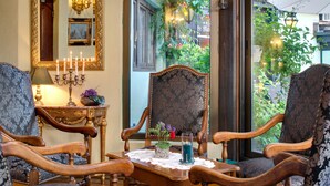 Una habitación con una mesa de madera, dos sillas tapizadas, un espejo y un candelabro con velas encendidas.