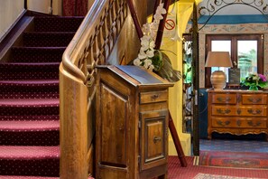 Una escalera con barandilla de madera y un mueble de madera con un arreglo floral.