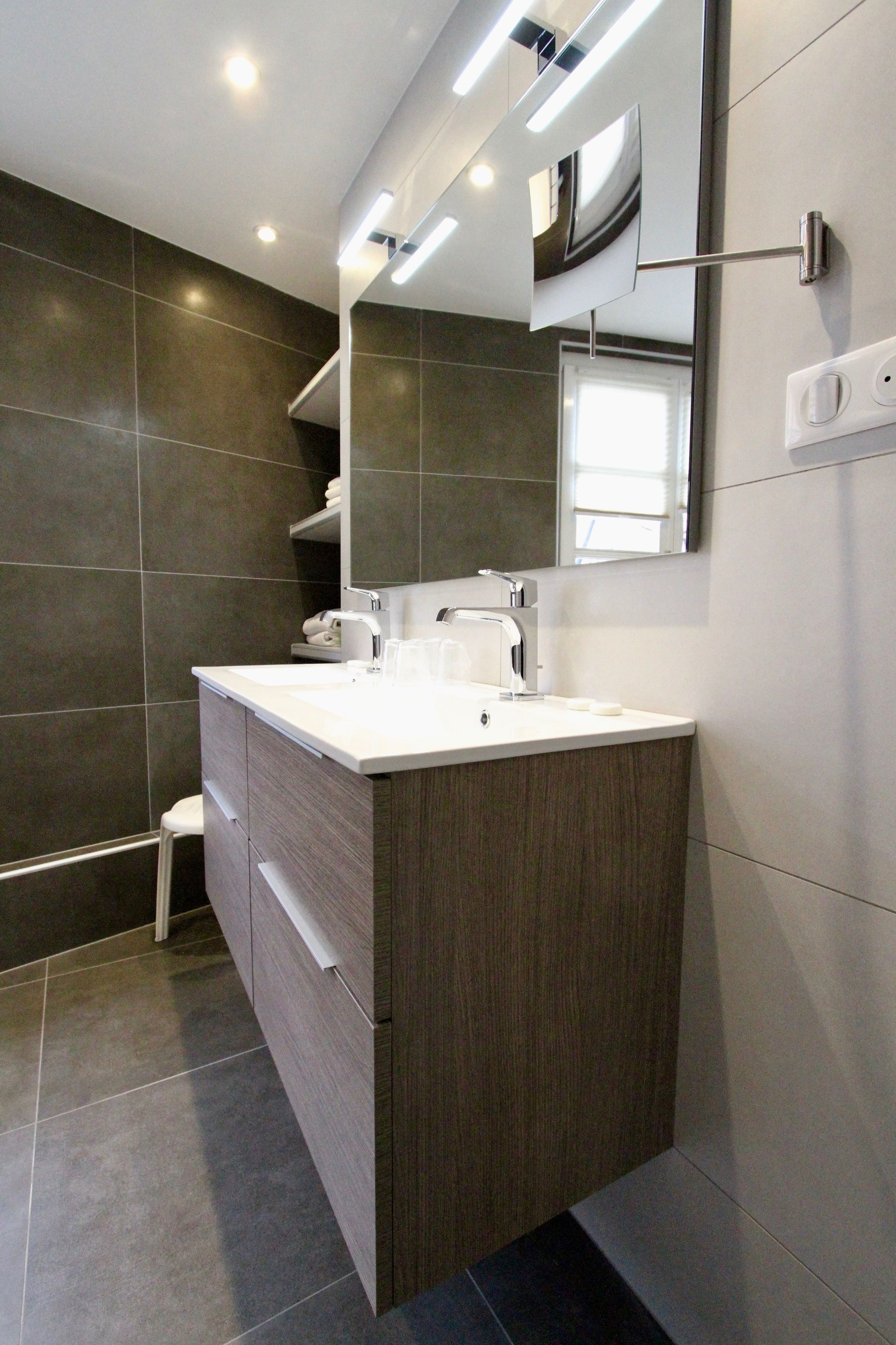 A modern bathroom with a large vanity, a mirror, and a shower area.