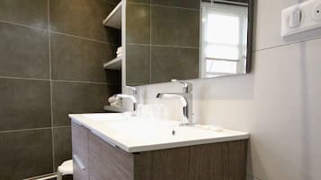 A modern bathroom with a large vanity, a mirror, and a shower area.