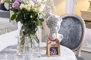 Una mesa con un jarrón de flores, un busto y una bolsa de regalo.