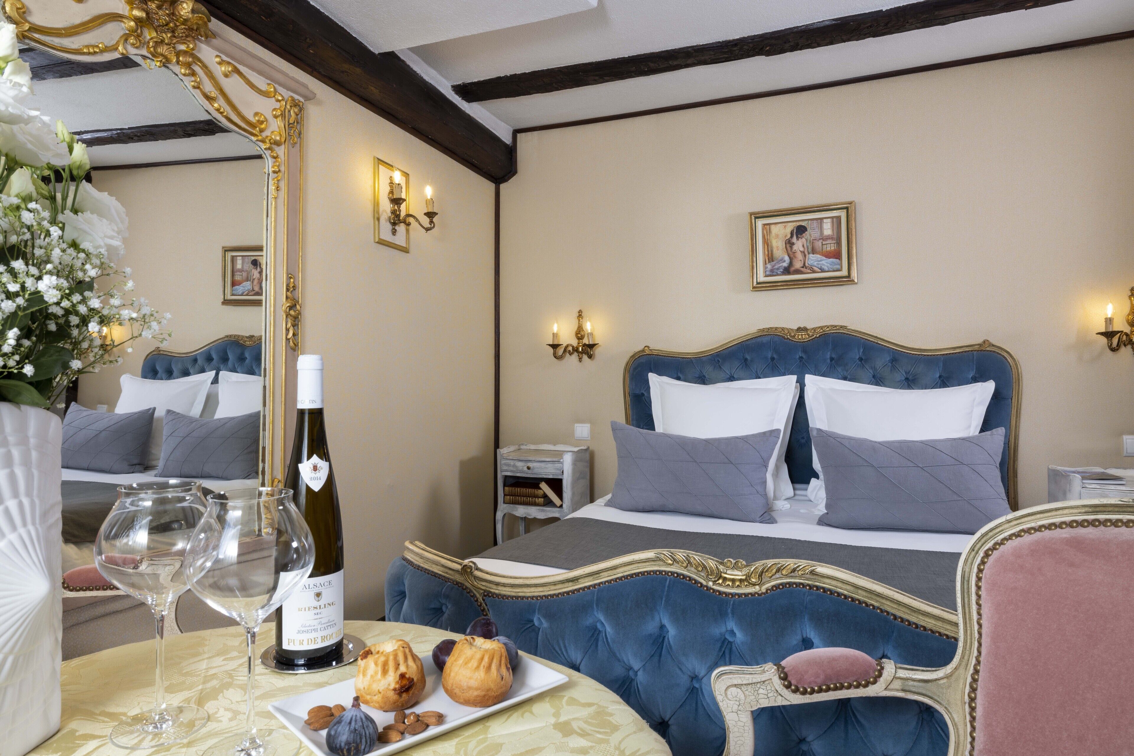 Un dormitorio lujoso con una cama grande, una mesita de noche con una botella de vino, dos copas y un plato de pasteles.