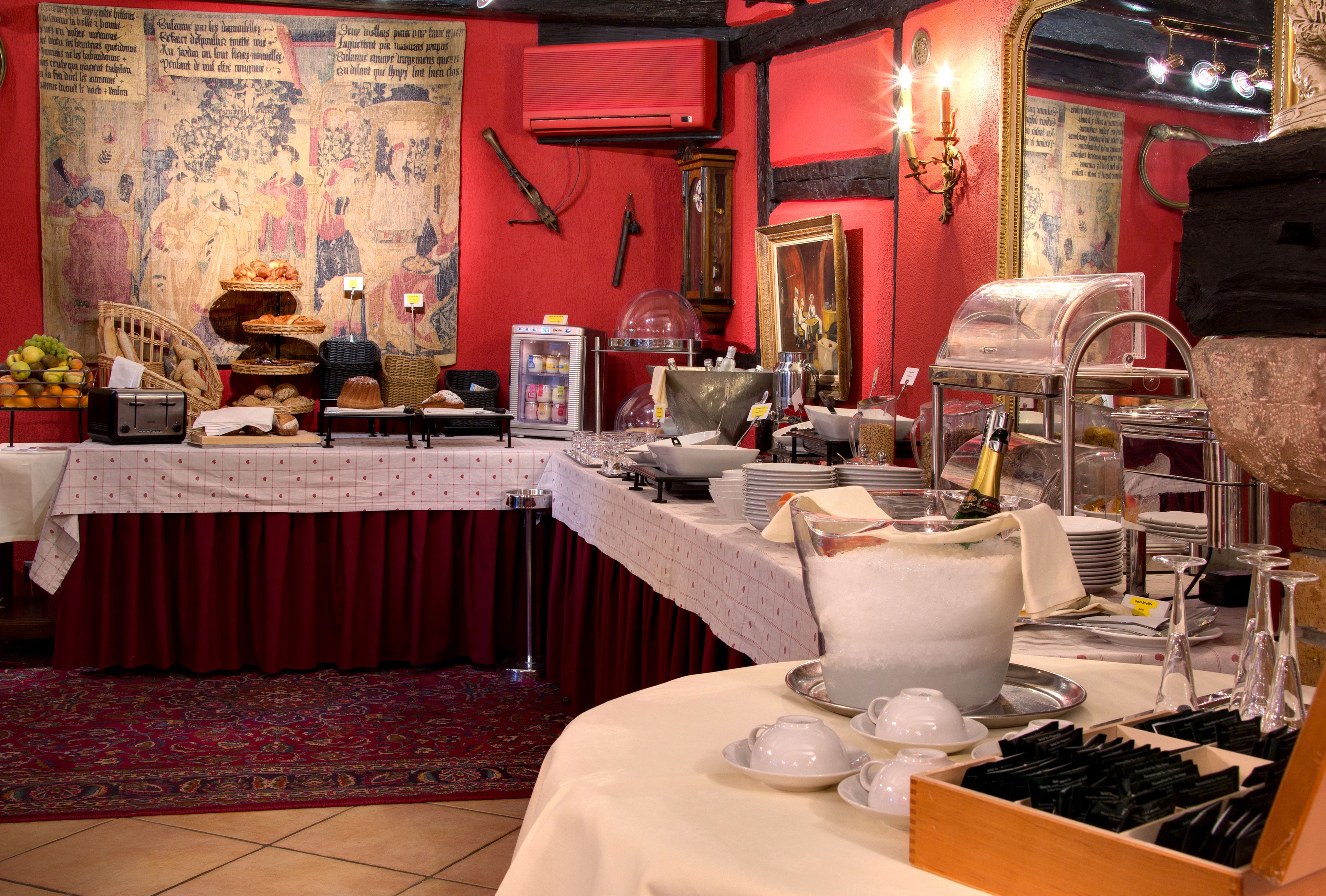 A buffet setup with various food items and utensils, a refrigerator, and a decorative wall with a tapestry.