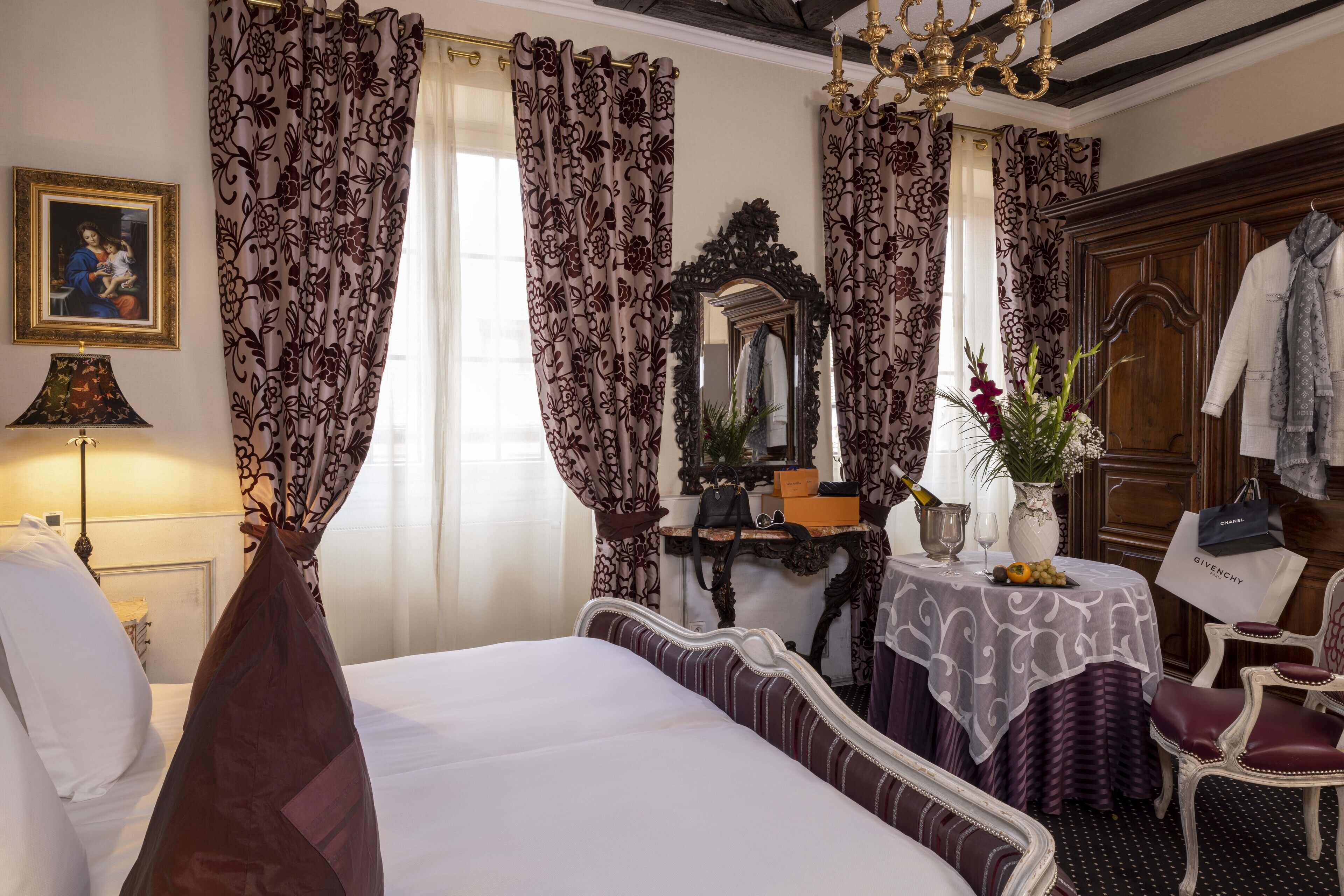 A hotel room with a bed, a vanity table with a mirror, a dressing table, and a chair.