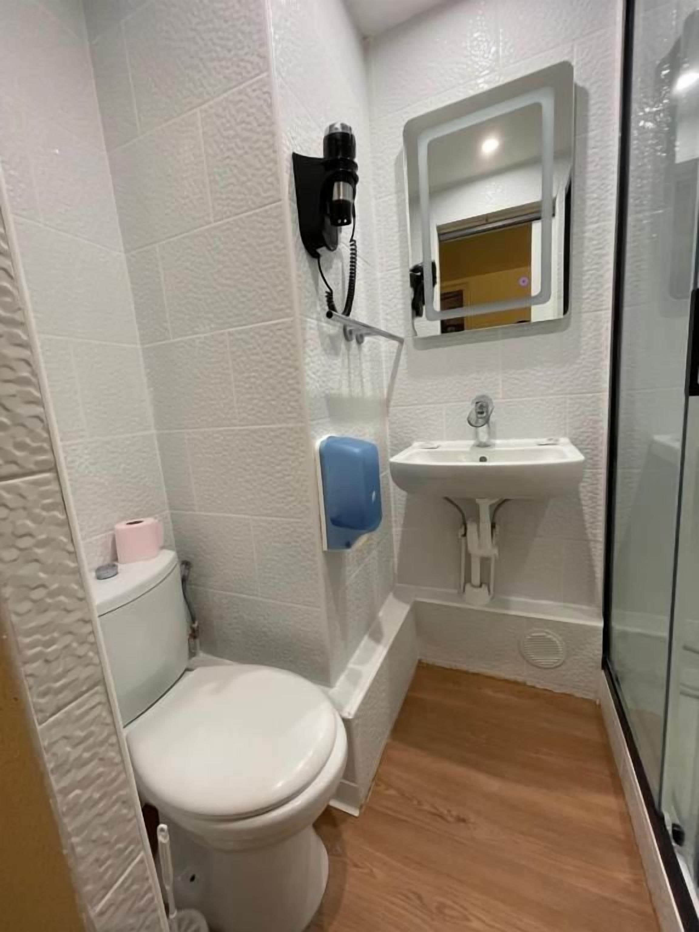 Une petite salle de bain comprenant des toilettes, un lavabo et un espace douche.