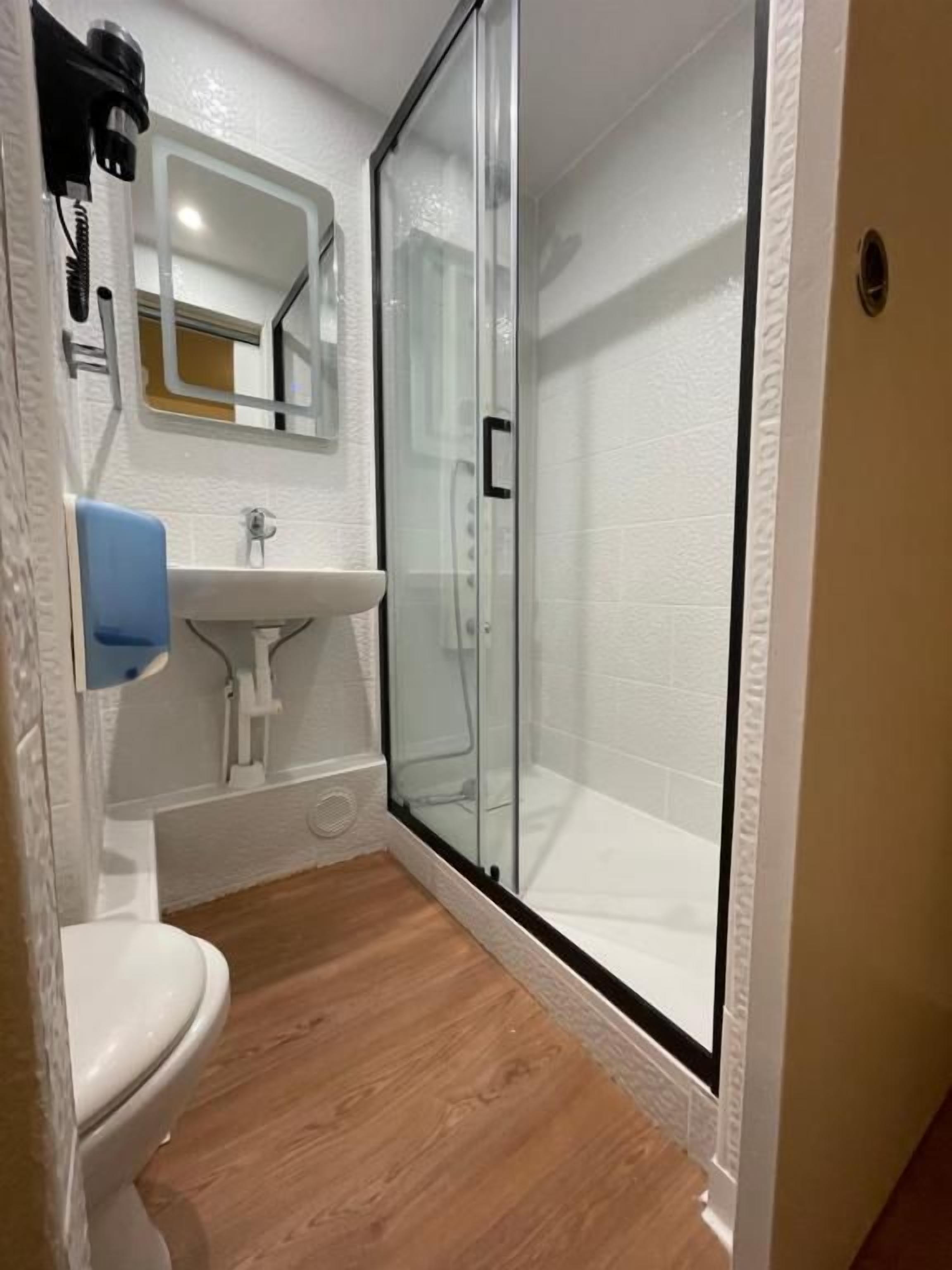 A bathroom with a glass-enclosed shower, a white sink, and a toilet.