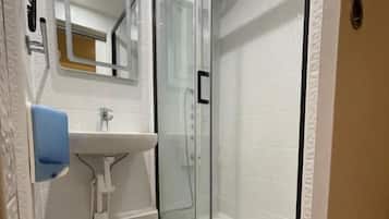 A bathroom with a glass-enclosed shower, a white sink, and a toilet.