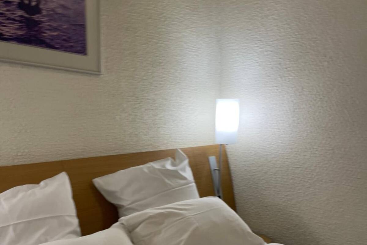A neatly made bed with white linens in a hotel room.