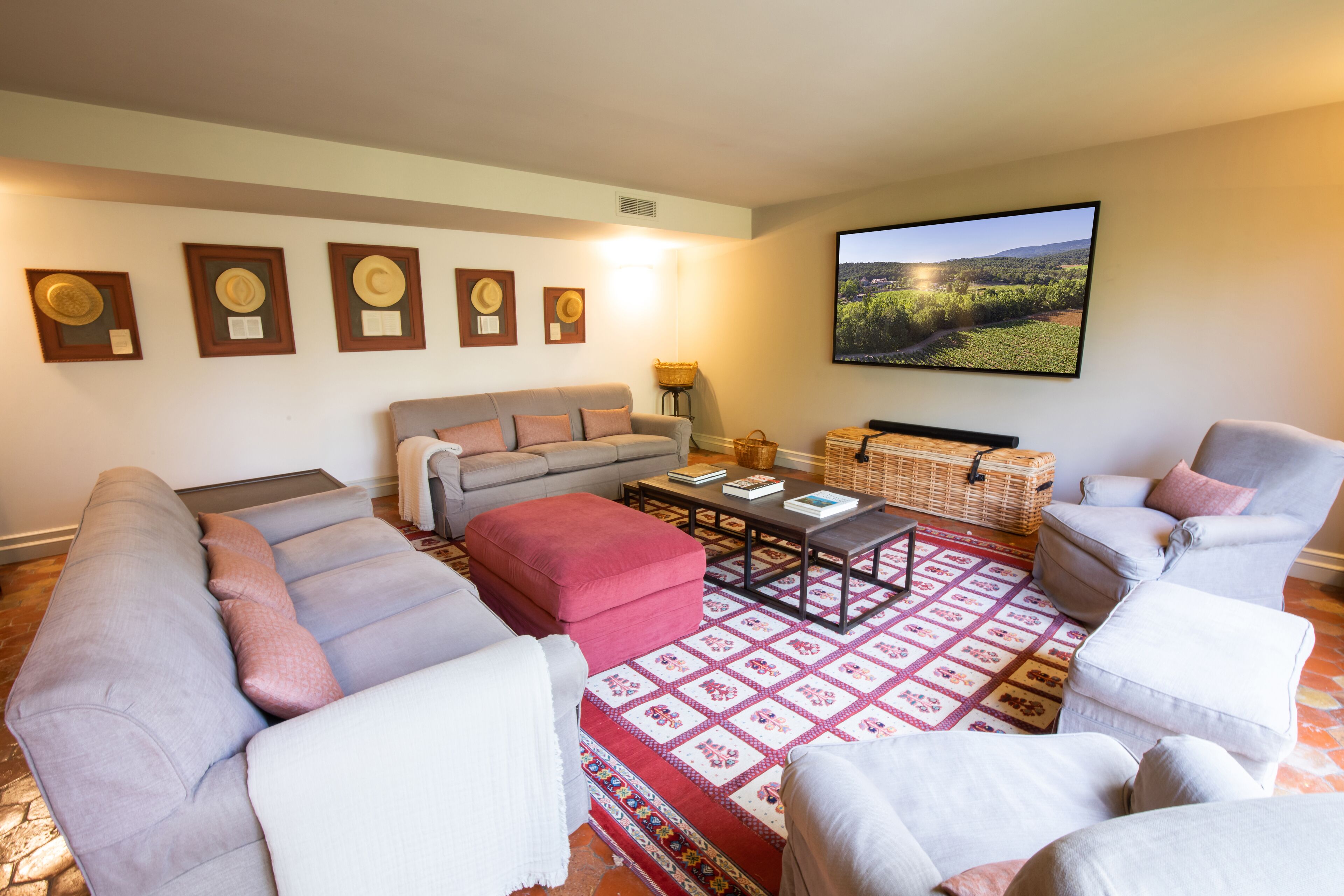 A living room with a sofa, armchairs, a coffee table, and a large TV screen.