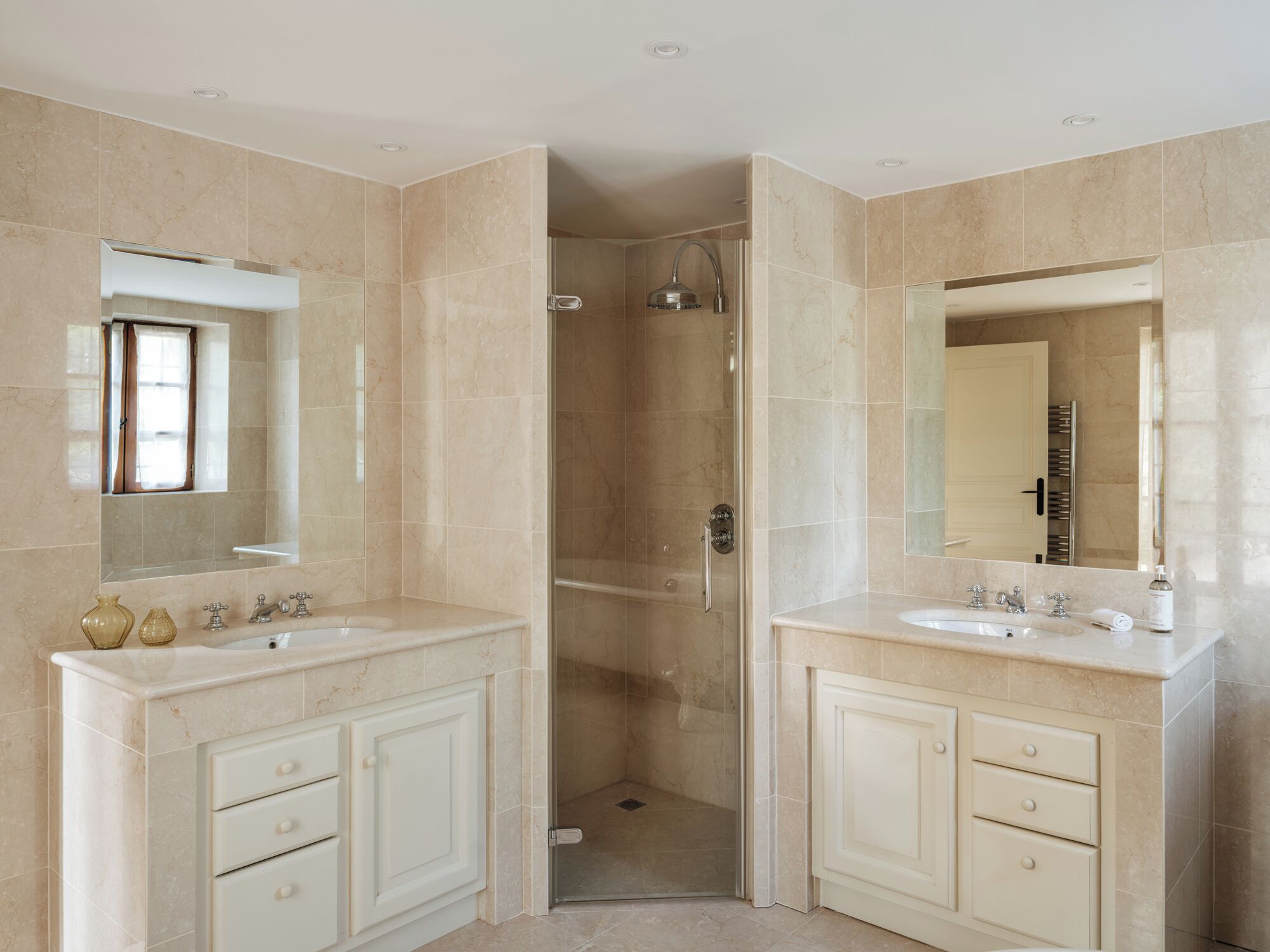 Un baño moderno con dos lavamanos, ducha y zona de ducha con mampara de vidrio.