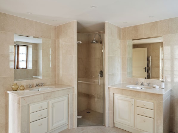 A modern bathroom with two sinks, a shower, and a glass-enclosed shower area.