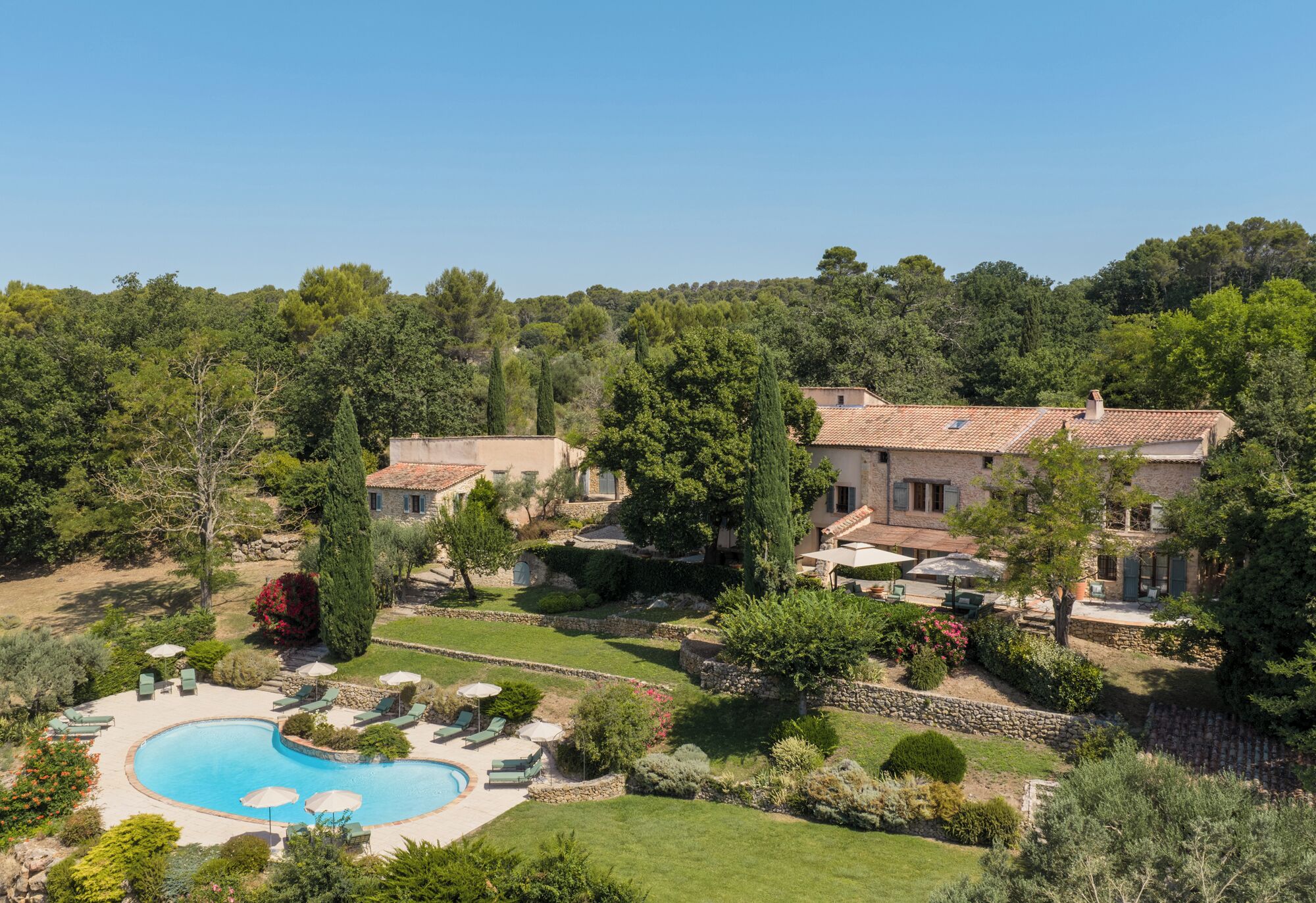 Una villa con piscina, immersa nel verde e alberi.