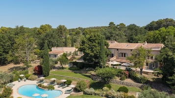 Eine Villa mit Swimmingpool, umgeben von üppigem Grün und Bäumen.