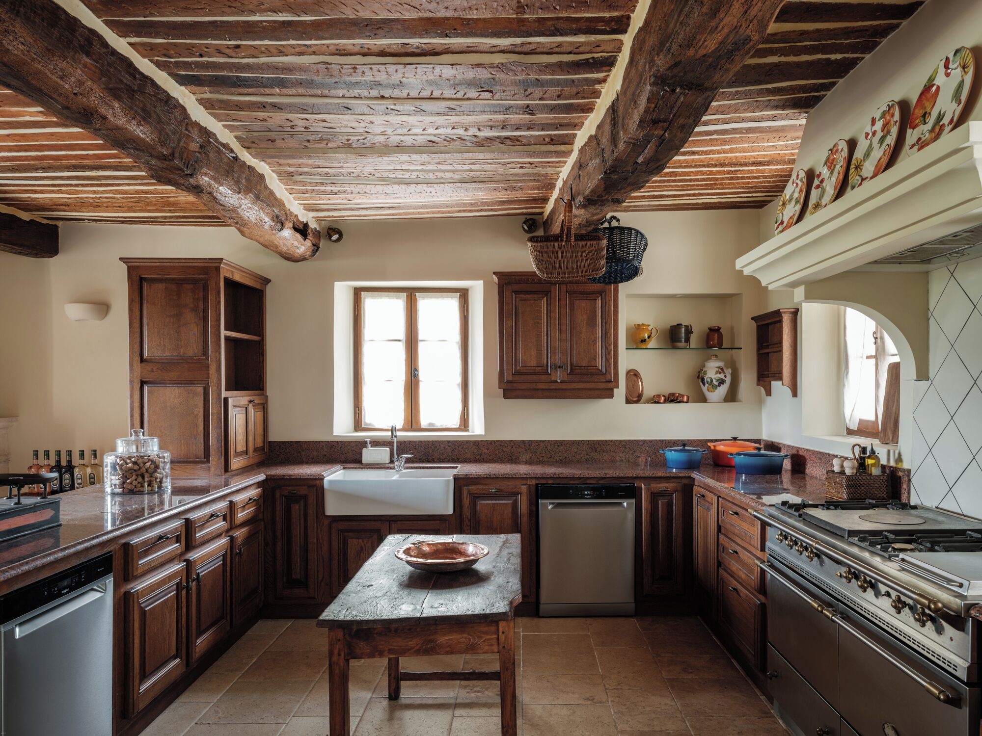 A rustic kitchen with wooden cabinets, a stone countertop, a built-in oven, and a window.