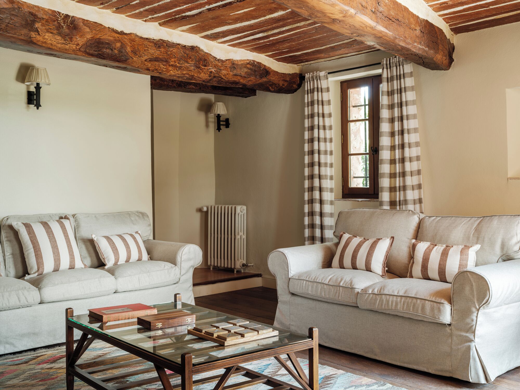 Una sala de estar con dos sofás, una mesa de centro de vidrio y techo de madera.
