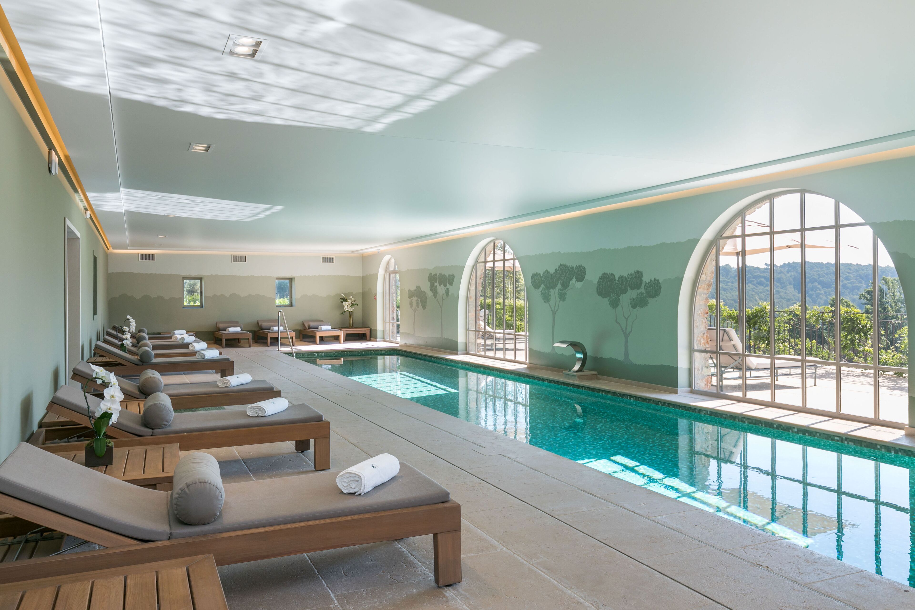 A spa area with a pool, sun loungers, and a view of the mountains.