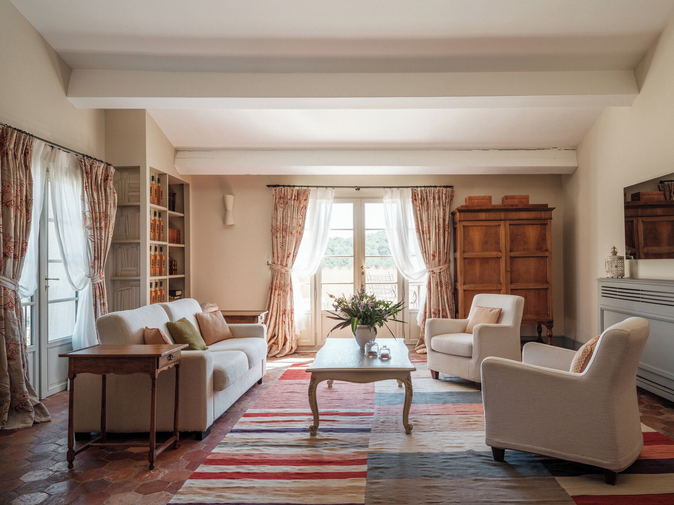 Una sala de estar con un sofá, sillones, una mesa de centro y una estantería.