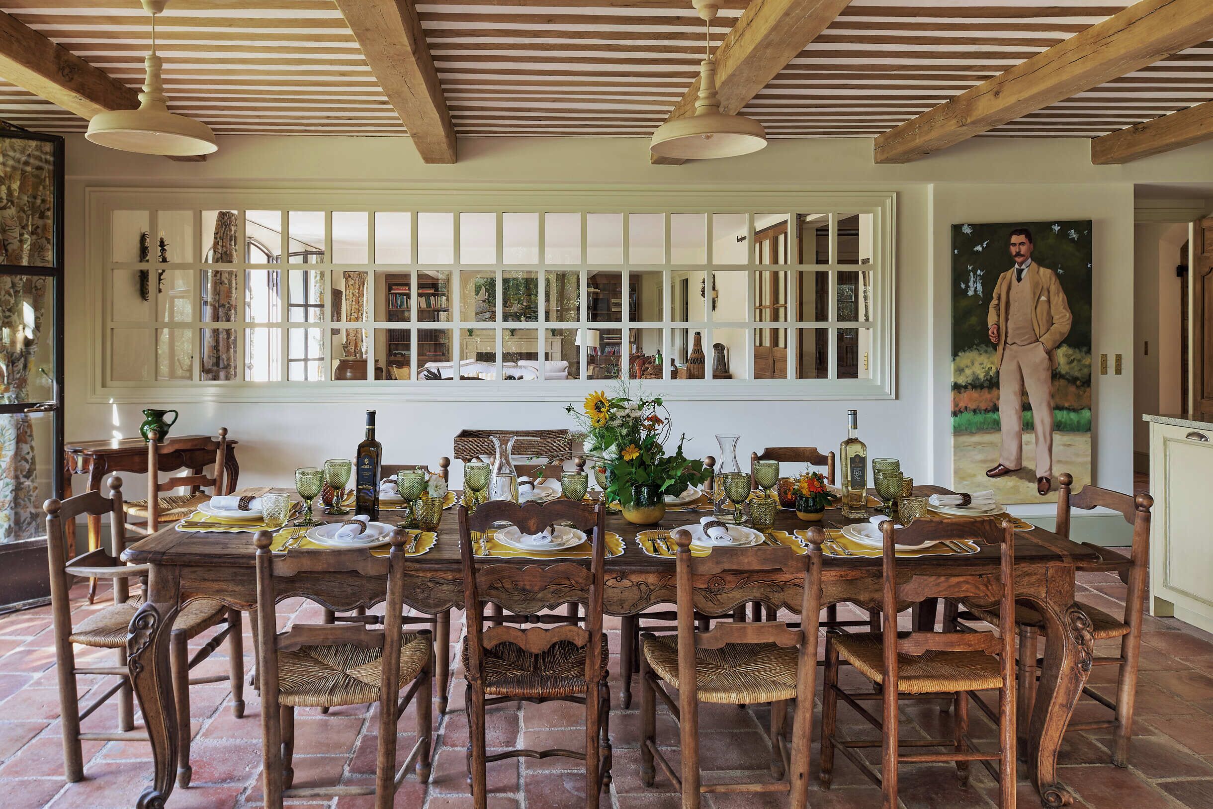 A dining area with a wooden table set for six, surrounded by wicker chairs.