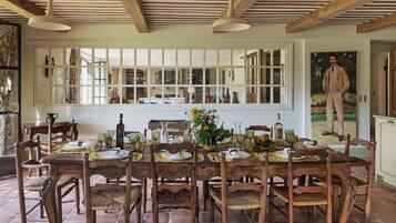 Comedor con mesa de madera dispuesta para seis personas, rodeada de sillas de mimbre.