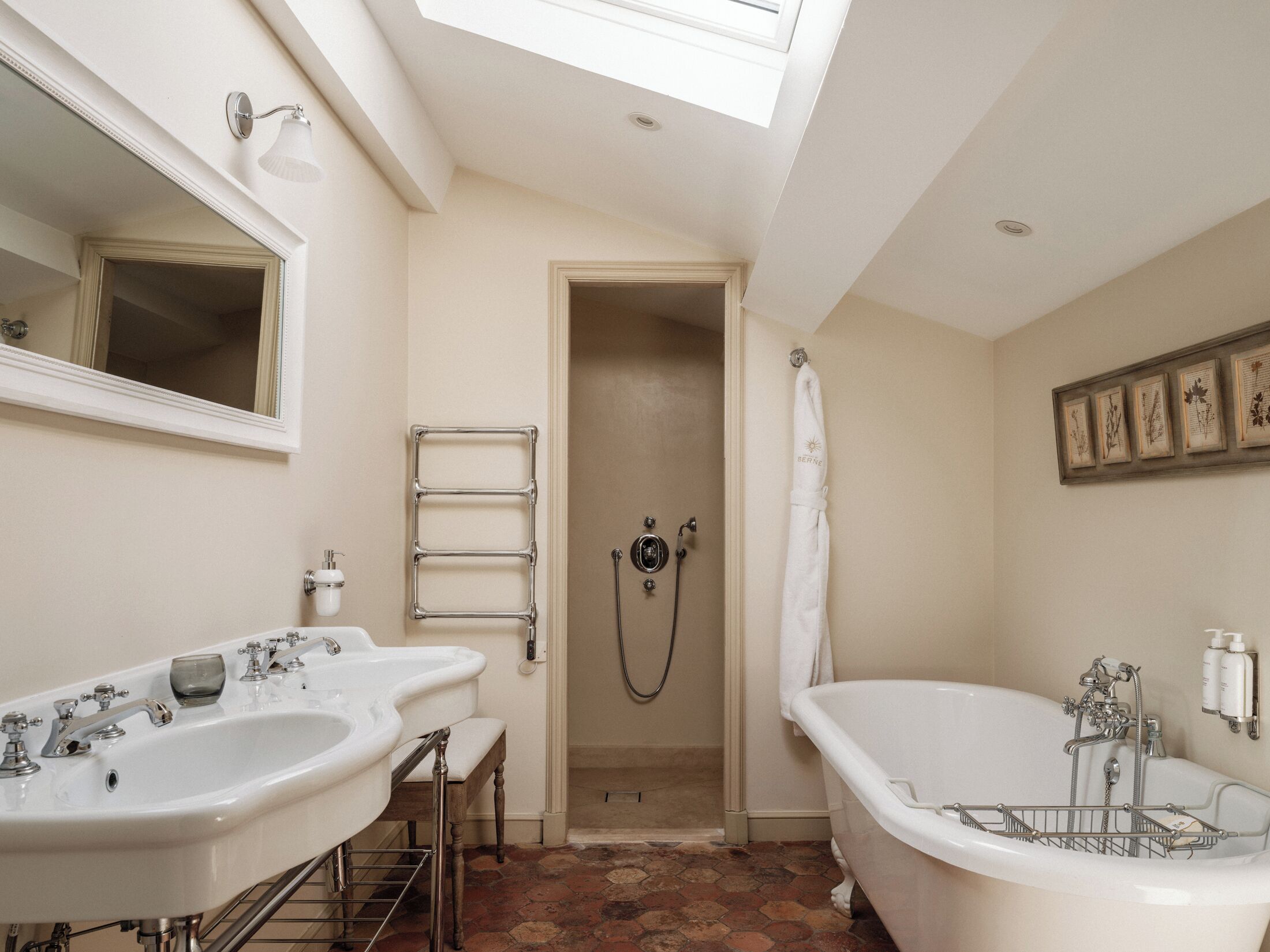 Une salle de bain avec deux lavabos, une baignoire, une douche et une fenêtre de toit.