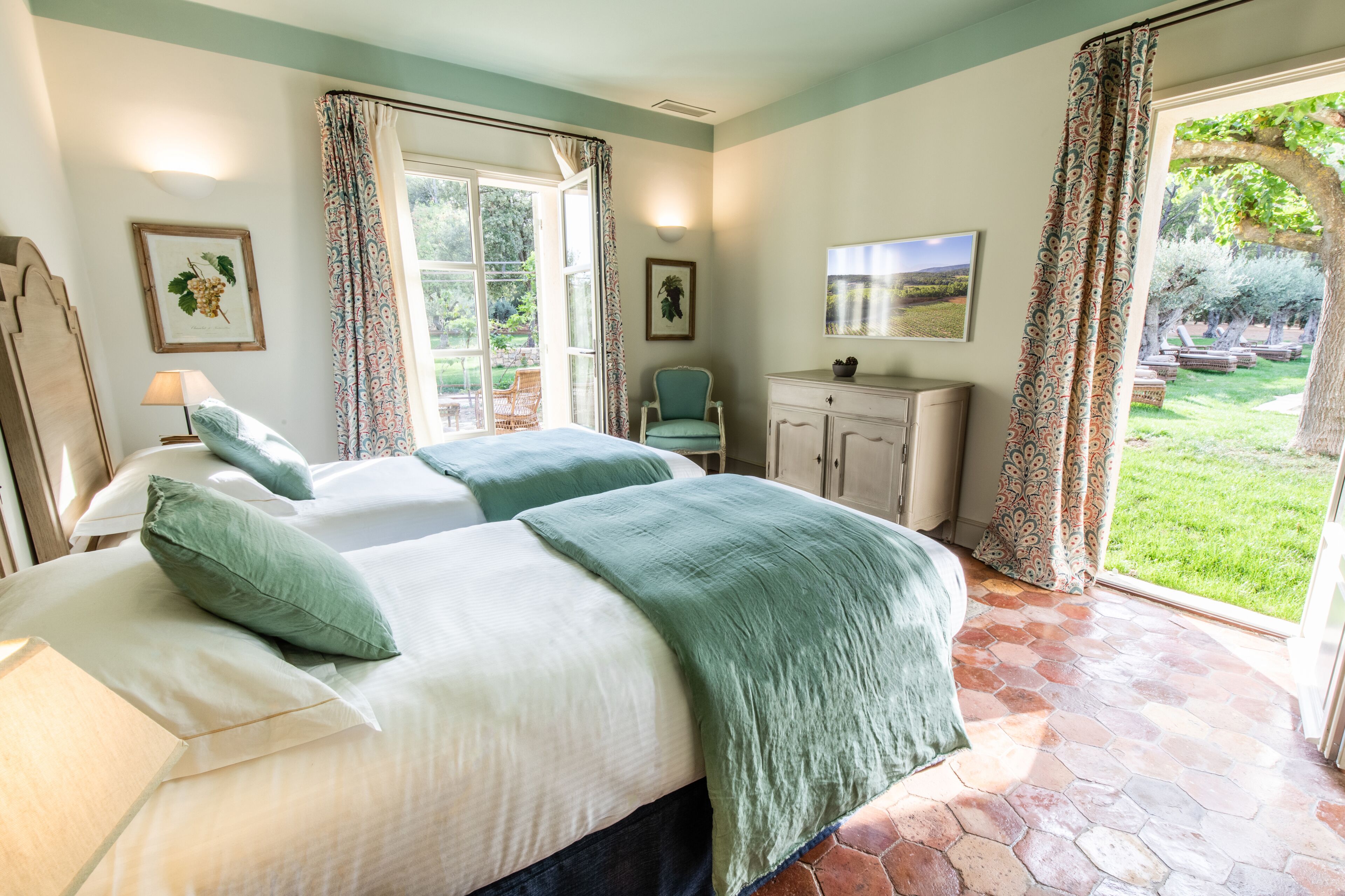 Une chambre avec deux lits, un bureau et une vue sur le jardin.