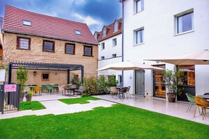 A courtyard with outdoor seating, a pergola, and a well-maintained lawn.