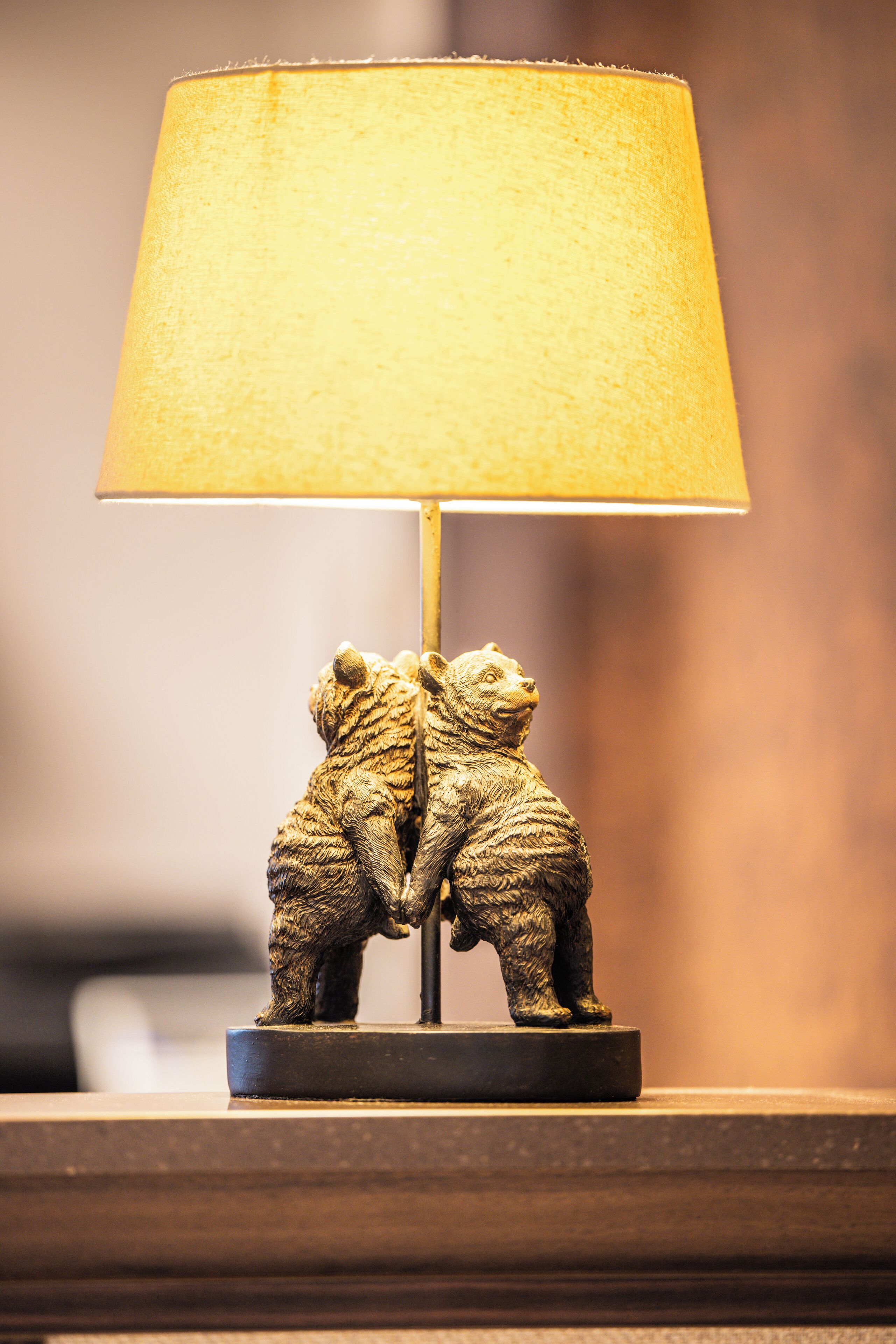 Une lampe dont le pied est orné d’une figurine d’ours et qui est surmontée d’un abat-jour jaune.