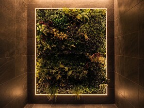 Pared cuadrada con un jardín empotrado que exhibe diversas plantas y una cálida fuente de luz.
