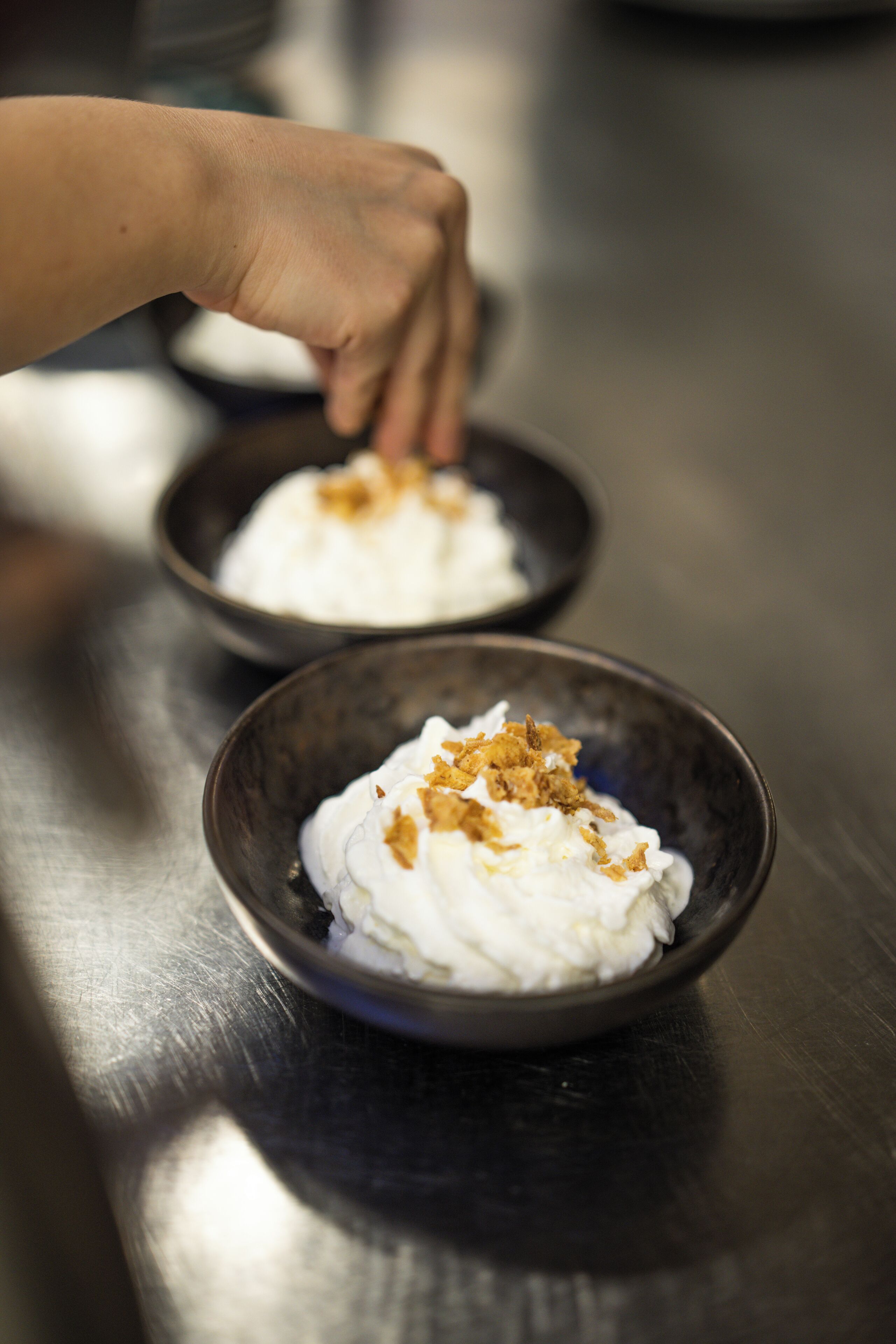 A hand placing a dessert in a bowl.