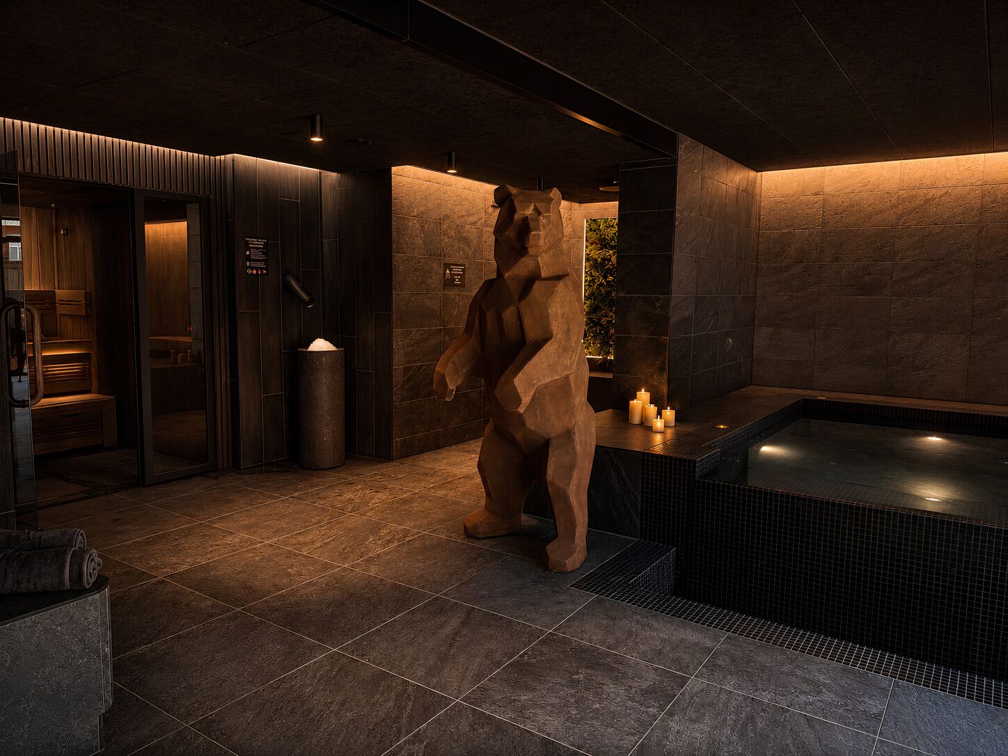 Un espace de bien-être doté d’un mur en pierre, d’un jacuzzi et d’une sculpture.