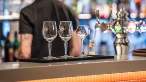A bar area with a counter, glasses, and bottles in the background.
