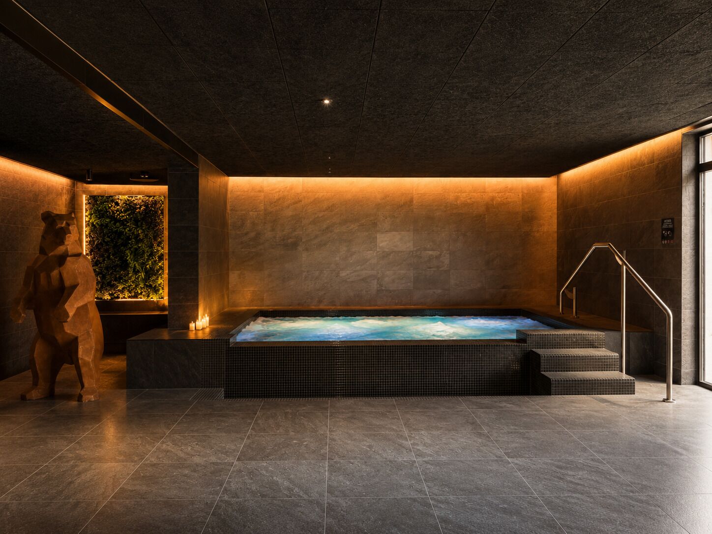 A spa area with a hot tub, tiled flooring, and a wall with a vertical garden.