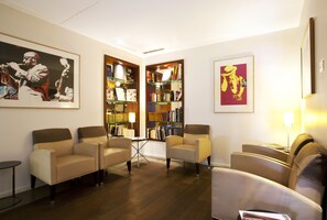 A modern living room with a sofa set, a bookshelf, and framed artwork on the walls.