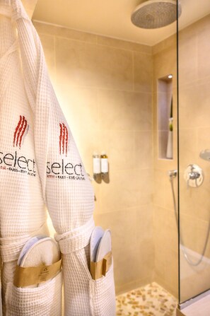 A bathroom with a shower, a towel rack with towels, and toiletries on the wall.