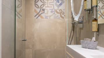 Un baño moderno con ducha de vidrio, tocador con espejo y salpicadero de azulejos.