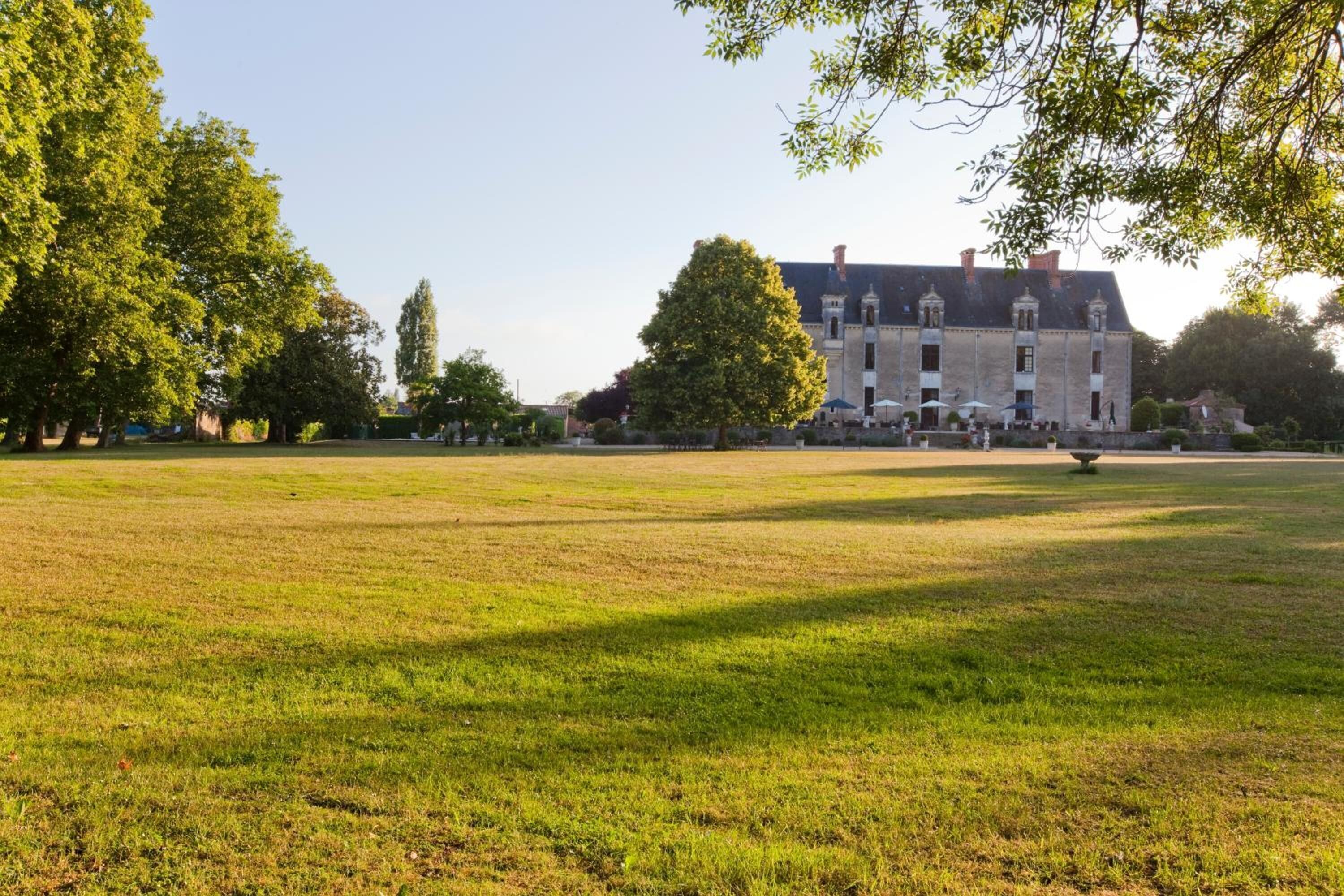 Un vaste champ herbeux, dégagé, avec un bâtiment historique en arrière-plan.