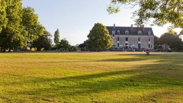 Un vaste champ herbeux, dégagé, avec un bâtiment historique en arrière-plan.