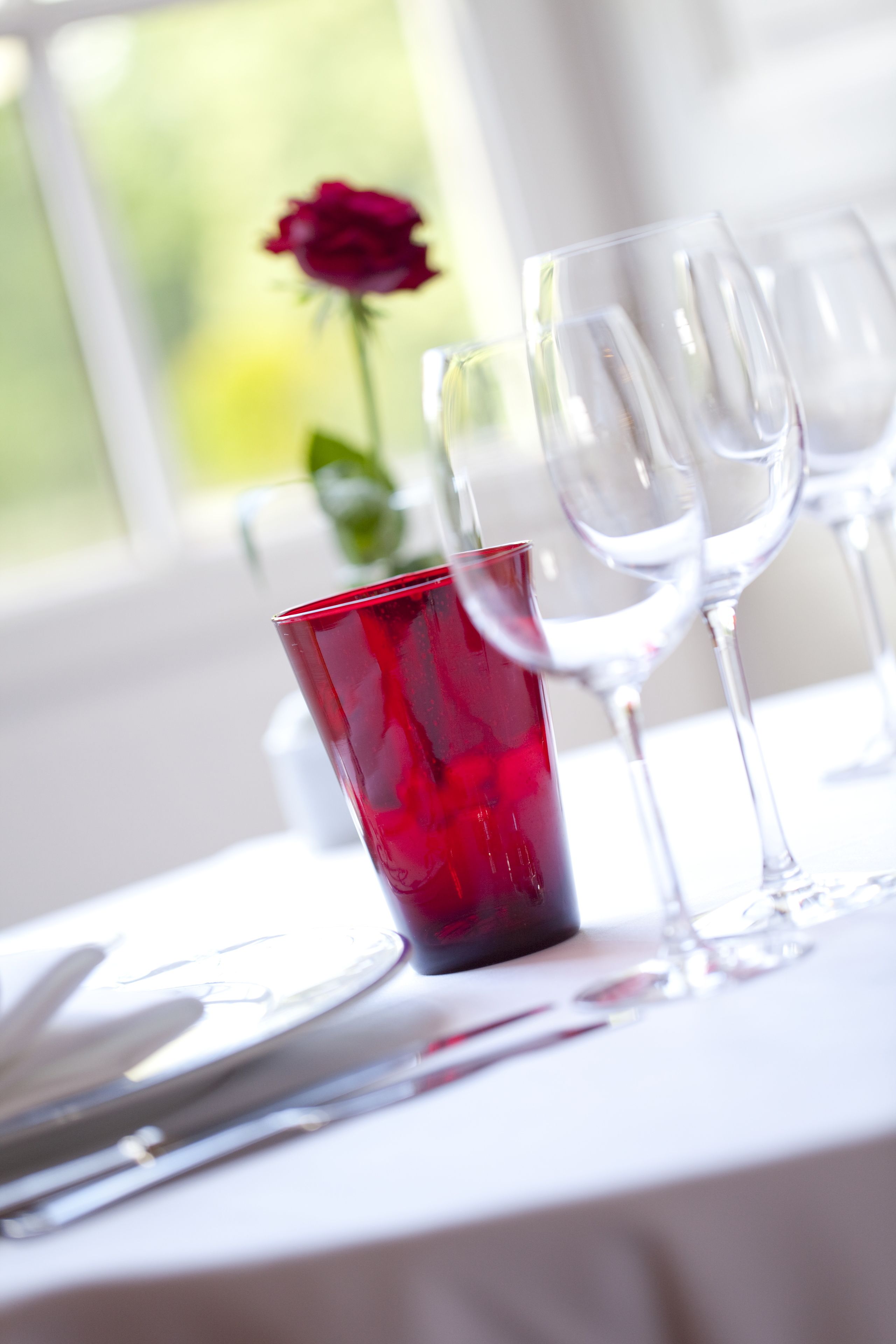 A table set with wine glasses and a red glass.